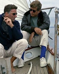 two men sitting on the deck of a sailboat