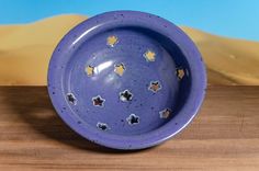 a purple bowl sitting on top of a wooden table next to a desert scene behind it