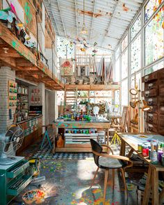 an artist's studio with lots of clutter on the floor and shelves full of art supplies