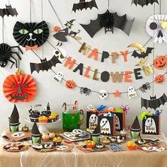 a table topped with lots of halloween decorations and paper bats hanging from it's ceiling