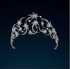 a tiara with stars and flowers on it's headpiece, against a dark blue background