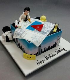 a birthday cake with a man sitting on top of it and writing on the paper