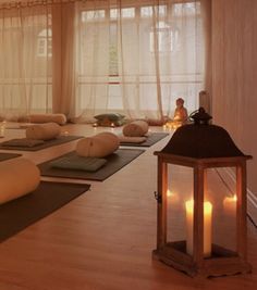 a yoga room with candles lit up on the floor and large windows in the background