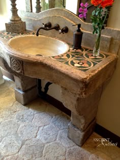 a bathroom sink sitting under a mirror next to a vase with flowers on top of it