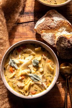 a bowl of pasta and bread on a wooden table next to a loaf of bread