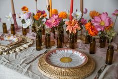 a table topped with plates and vases filled with flowers