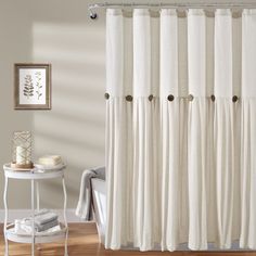 a white shower curtain in a bathroom next to a table and chair with towels on it