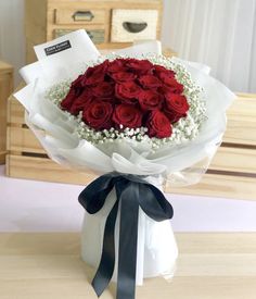 a bouquet of red roses with baby's breath tied around it on a table