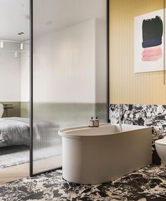 a bathroom with a bathtub, toilet and rug on the floor in front of a bed