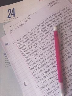 a pink pen sitting on top of a pile of paper