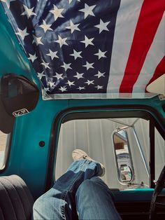 a man sitting in the drivers seat of a truck with an american flag on it