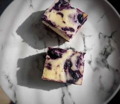 two pieces of blueberry cheesecake on a white plate with marble countertop top