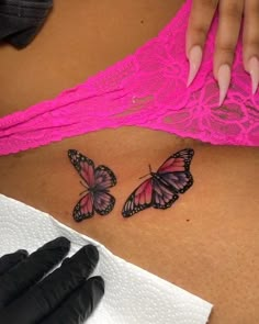 a woman's stomach with two butterfly tattoos on her belly and black gloves next to it