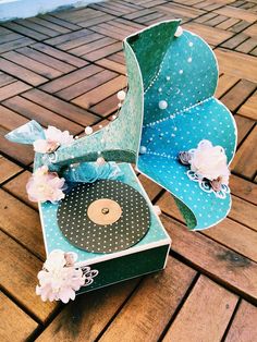 a record player sitting on top of a wooden floor next to flowers and pearls in it