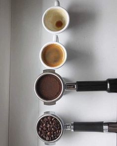 four cups of coffee are lined up on a table