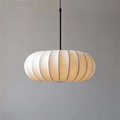 a white lamp hanging from a black cord on a gray wall in a living room