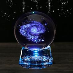 a crystal ball with stars in it on a wooden table next to a black background