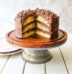 a chocolate cake on a wooden plate with one slice cut out and ready to be eaten