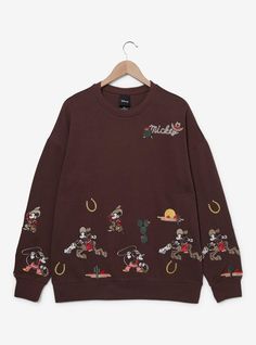 Head to the wild west in style with this Disney sweatshirt! Featuring embroidered designs of Mickey among cacti and horseshoes along the bottom and sleeves  the front of this crewneck includes "Mickey" lettering  perfect for trips to the rodeo or the Disney Parks.A BoxLunch Exclusive!60% cotton; 40% polyesterListed in unisex sizesWash cold with like colors; dry lowImported Disney Princess Outfits For Disneyland, Matching Disney Sweaters, Plus Size Winter Disney Outfits, Disney World Outfit Winter, Disneyland Outfit Christmas, Disney December Outfits, Cozy Disneyland Outfit, Warm Disney Outfits, Comfy Disney Outfits Winter