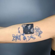 a person's arm with a blue and white flower tattoo on it