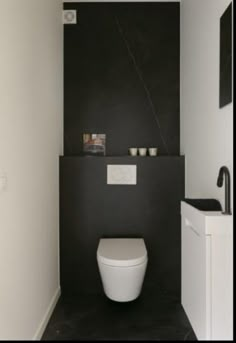 a white toilet sitting in a bathroom next to a black and white wall with pictures on it