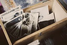 an open wooden box filled with photos on top of a table