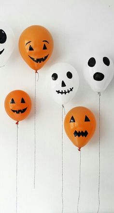 halloween balloons with faces and numbers hanging from strings in front of a white wall that says trick or treat