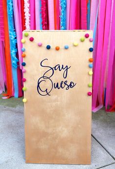 a sign that says say guess on it in front of colorful streamers and streamers