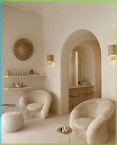 a living room filled with white furniture next to a wall mounted mirror and shelf on the wall