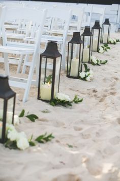 the aisle is lined with white flowers and lanterns