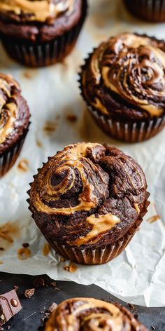 chocolate cupcakes with caramel swirl frosting on top sitting on wax paper