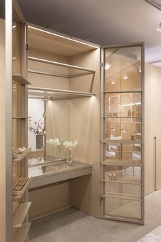 a woman walking past a desk in a room with shelving and shelves on the wall