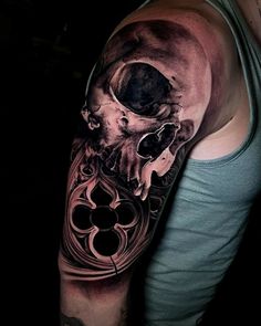 a man's arm with a black and white tattoo on it, featuring a skull