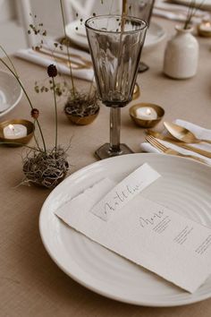 a table set with place cards, silverware and gold cutlery for an elegant dinner