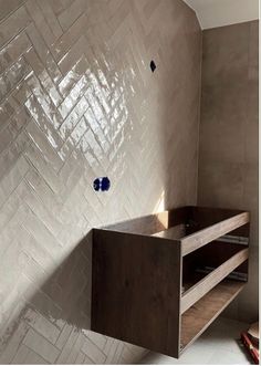 a bathroom with white tiled walls and wooden shelves