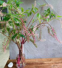 a vase filled with pink and white flowers on top of a wooden table next to a wall