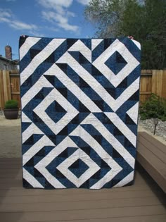 a blue and white quilt sitting on top of a wooden deck