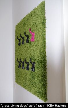 a green wall hanging on the side of a white wall with black and pink figures