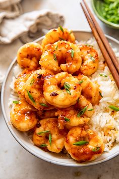 a bowl filled with shrimp and rice next to chopsticks