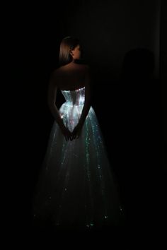 a woman standing in the dark with her hands on her hips wearing a light up dress