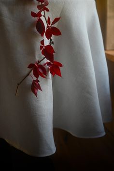 a white table cloth with red flowers on it and a wooden window sill in the background