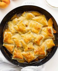 a skillet filled with food sitting on top of a white table next to oranges