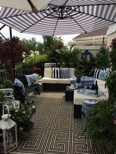 an outdoor living area with couches, tables and umbrellas