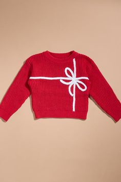 a red sweater with a white bow on the front and back, sitting on a tan background