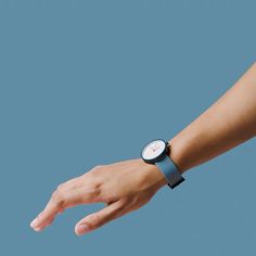 a woman's hand with a wrist watch on her left and right arm, against a blue background