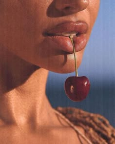 a woman holding a cherry in her mouth