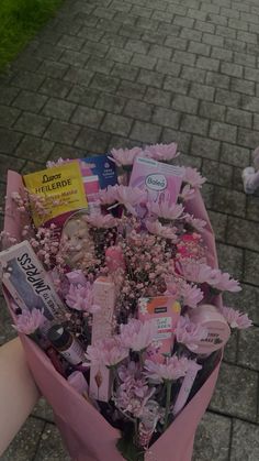 a person holding a bouquet of flowers on a sidewalk with other items in it and a stuffed animal nearby