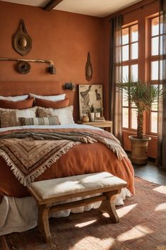 a bedroom with an orange wall and large bed covered in blankets, pillows and throw pillows