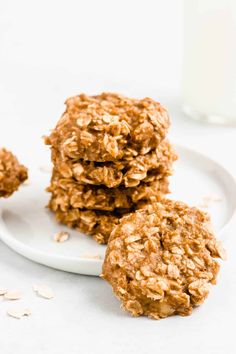 three oatmeal cookies on a white plate next to a glass of milk