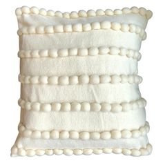 a white pillow with pom - poms on the front and back of it